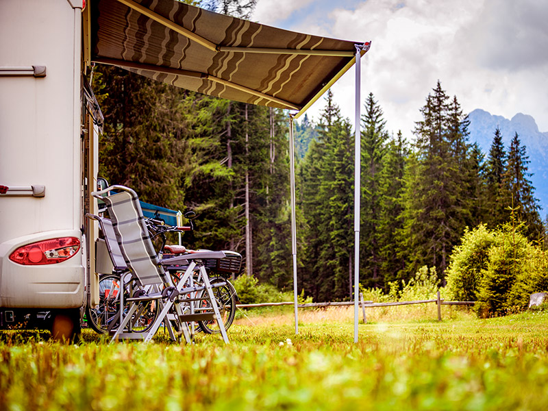 Camping chairs and bikes outside a caravan on a holiday in the mountains