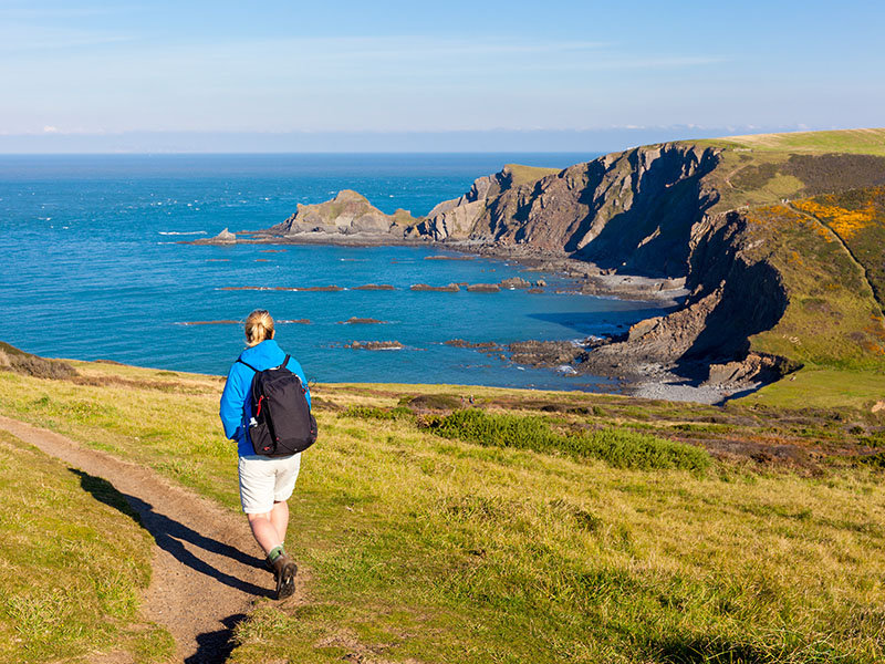A woman walking on the South West Coastal Path near Hartland Quay in North Devon, England, UK