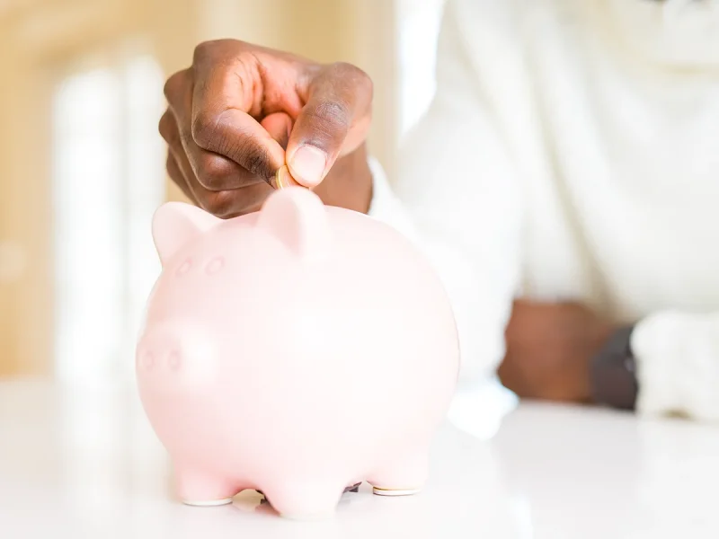 Close up of a man's hands putting a coin in a piggy bank