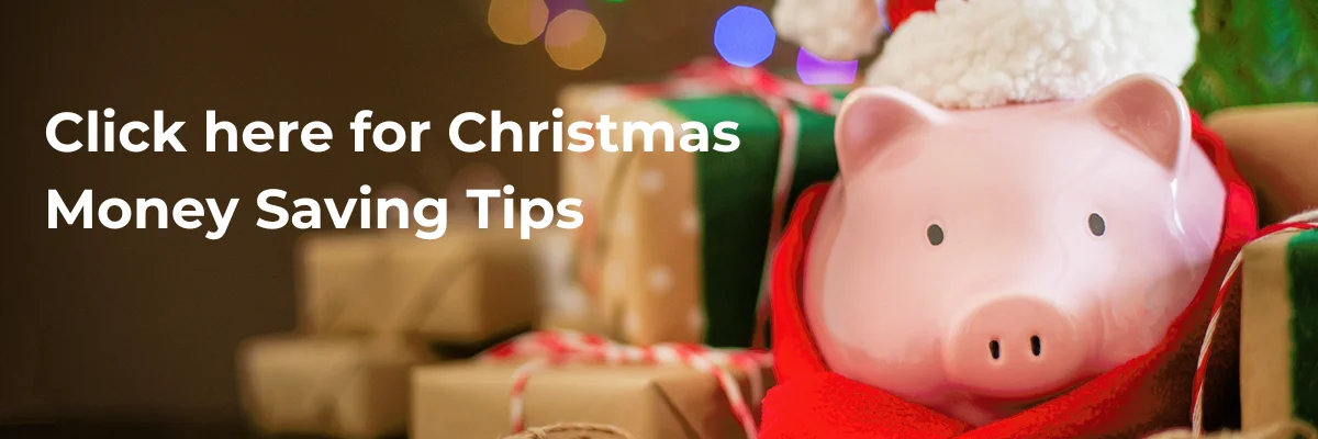 A pink piggy bank wearing a Santa hat and red scarf is surrounded by wrapped Christmas gifts against a backdrop of holiday lights. The text reads, "Click here for Christmas Money Saving Tips.