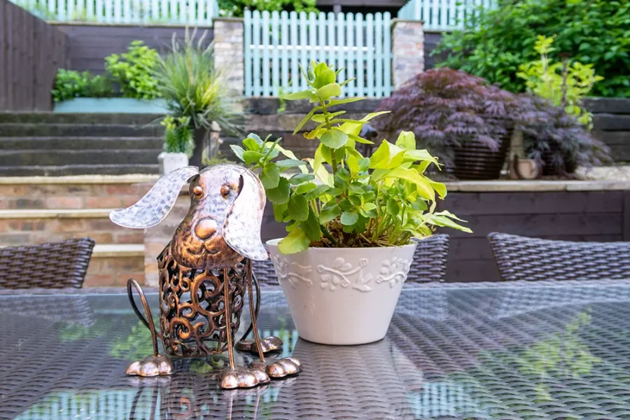 A metal dog ornaments on a patio table in a country cottage garden.