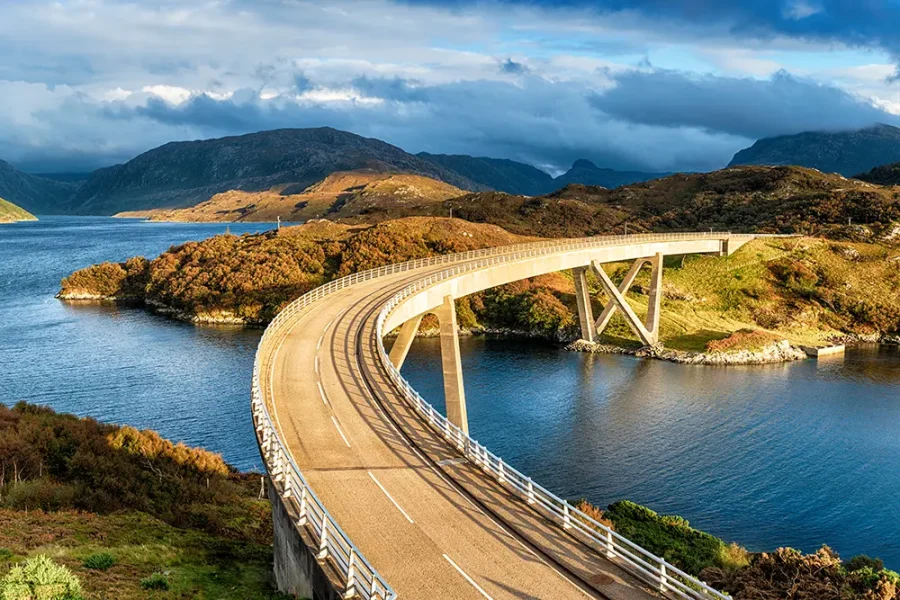 The curved Kylesku Bridge which crosses Loch a' Chàirn Bhàin in the Highlands of Scotland and forms part of the North Coast 500 scenic driving route.