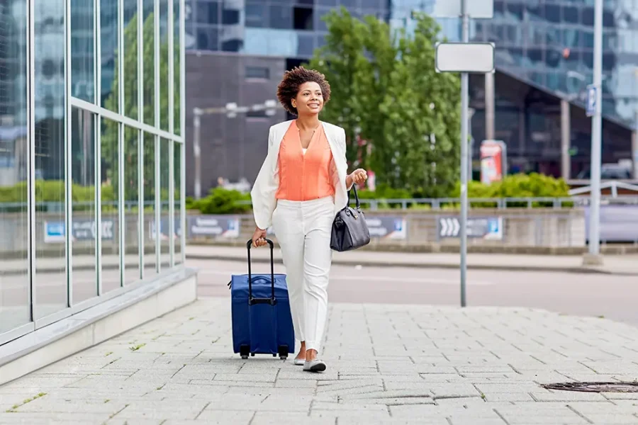 A business traveller walks confidently along the street, pulling her suitcase behind her.