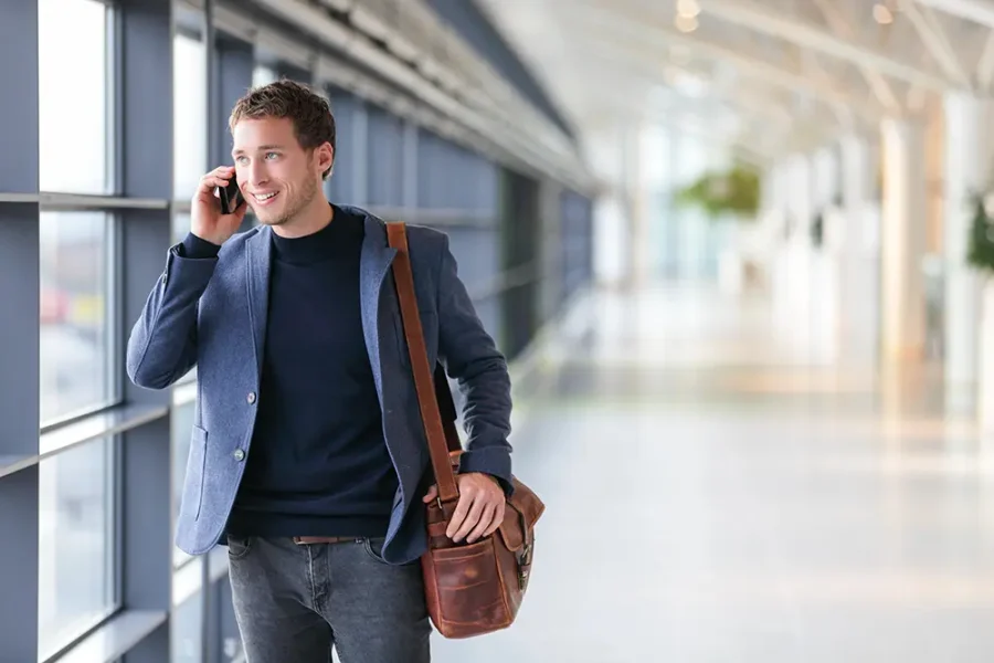 A casually dressed businessman talks on his mobile phone in the airport.