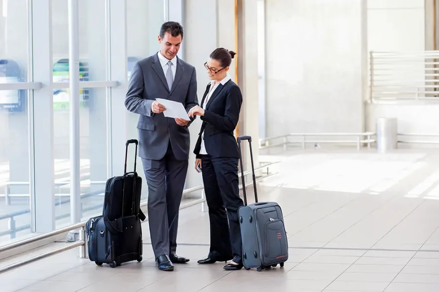 A business man and woman discuss work in the airport.