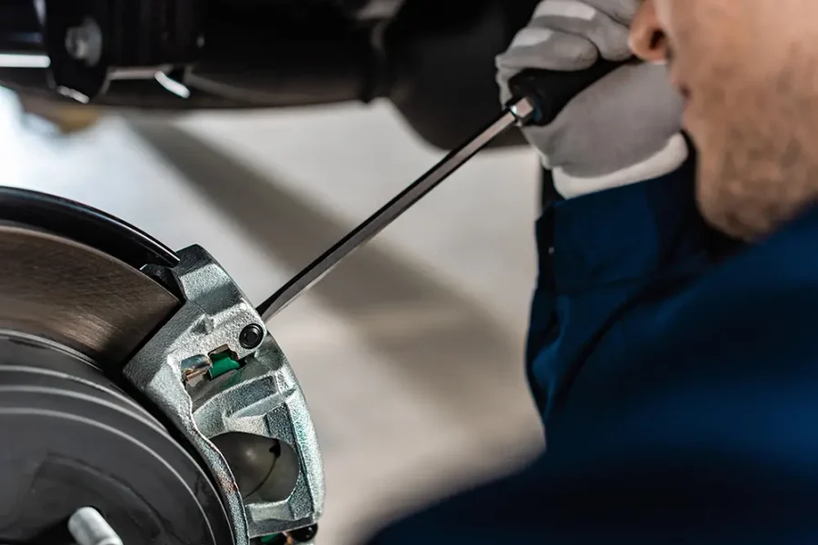 Close up of a car mechanic adjusting a car's brake caliper.