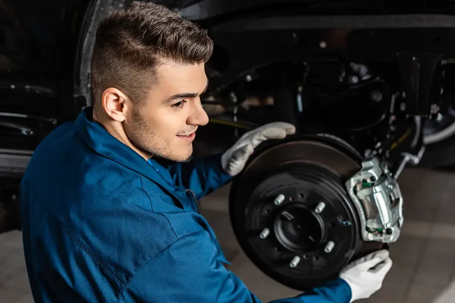 A car mechanic works on a car's brake disc.