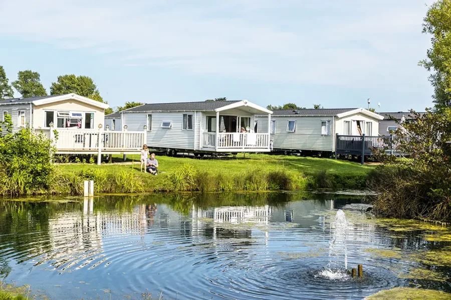 A row of park homes or static caravans overlooking a lake.
